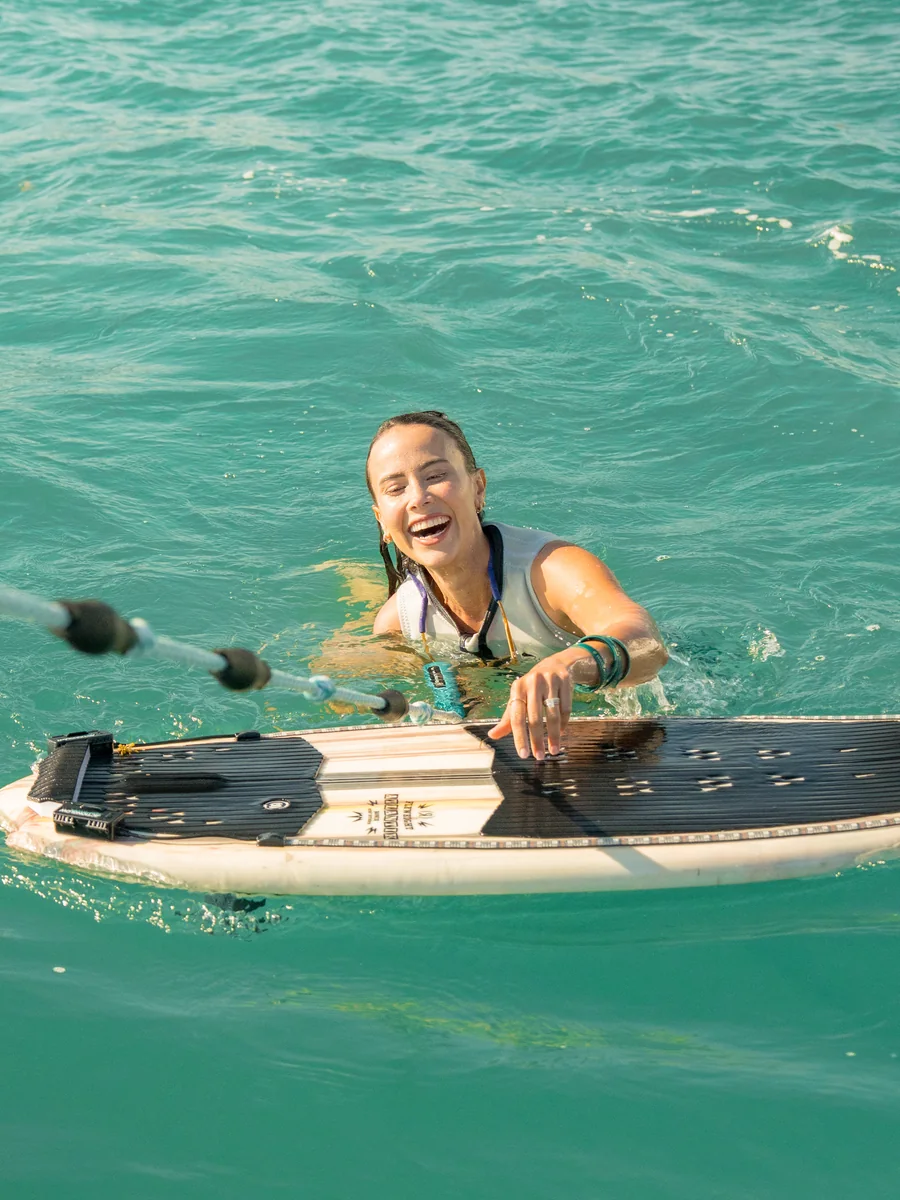 A smiling wakesurfer in Miami's turquoise water with a wakesurf board